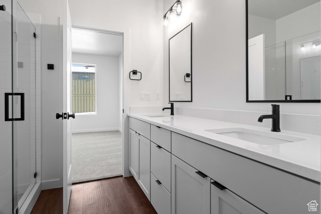 Bathroom featuring hardwood / wood-style floors, a shower with door, large vanity, and dual sinks