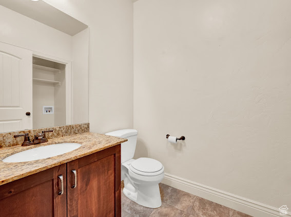 Bathroom featuring vanity with extensive cabinet space, tile floors, and toilet
