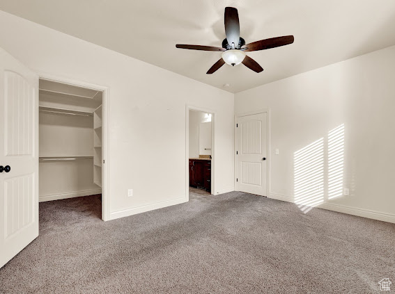 Unfurnished bedroom with ceiling fan, dark carpet, and a closet
