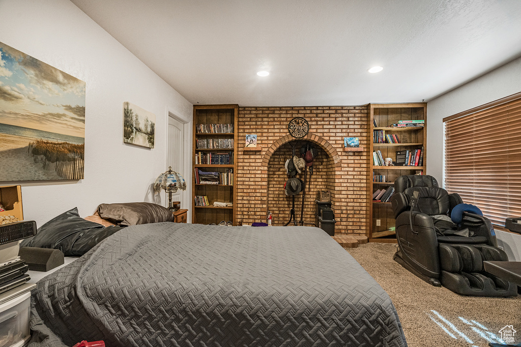 Carpeted bedroom featuring brick wall