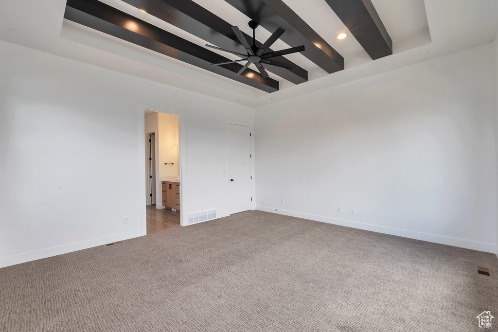 Carpeted empty room with a tray ceiling, beamed ceiling, and ceiling fan