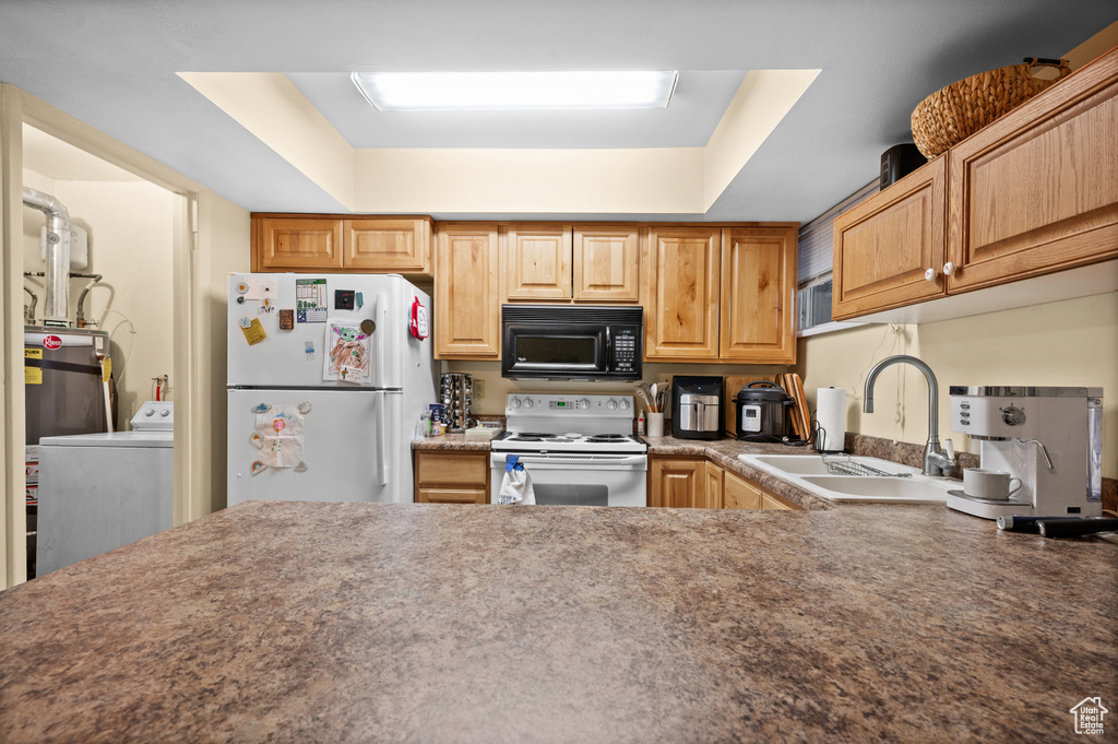 Kitchen with white appliances, washer / clothes dryer, a raised ceiling, and sink