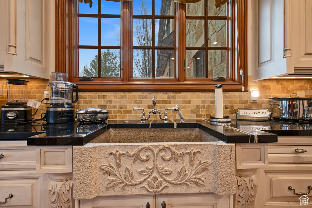 Kitchen with white cabinets, dark stone counters, sink, and tasteful backsplash