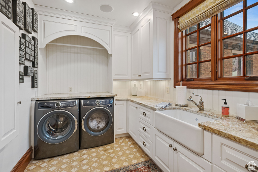 Clothes washing area with cabinets, sink, independent washer and dryer, and light tile floors