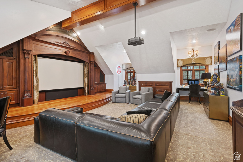 Home theater with lofted ceiling with beams and light carpet