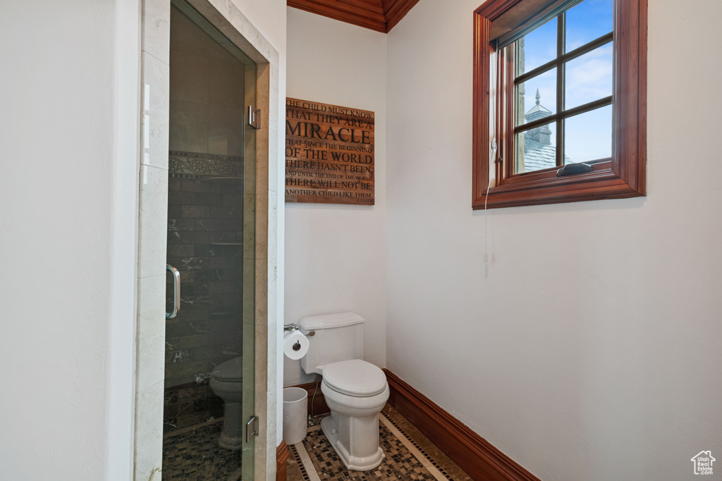 Bathroom featuring toilet, a shower with door, and tile flooring