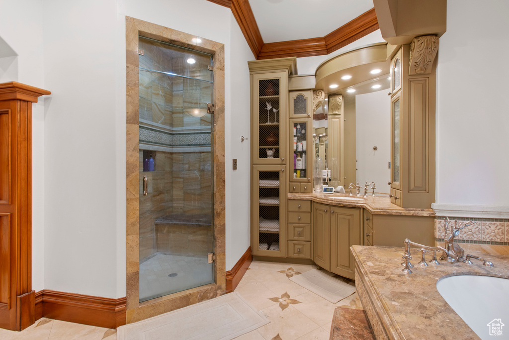 Bathroom featuring vanity, ornamental molding, tile flooring, an enclosed shower, and decorative columns