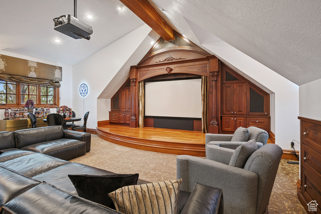 Cinema room featuring vaulted ceiling with beams, dark carpet, and a textured ceiling