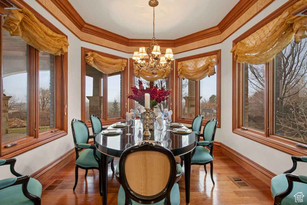 Dining space with hardwood / wood-style flooring, a notable chandelier, and ornamental molding