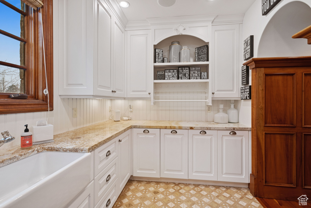Kitchen with white cabinetry, sink, and tasteful backsplash
