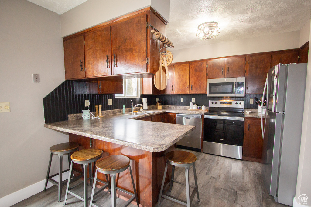 Kitchen with backsplash, a kitchen breakfast bar, dark hardwood / wood-style flooring, sink, and stainless steel appliances