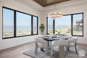 Dining room with a notable chandelier, a mountain view, hardwood / wood-style floors, and a tray ceiling