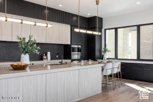 Kitchen featuring light hardwood / wood-style floors, stainless steel double oven, tasteful backsplash, and sink