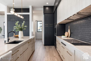 Kitchen with sink, light hardwood / wood-style flooring, decorative light fixtures, and light brown cabinetry