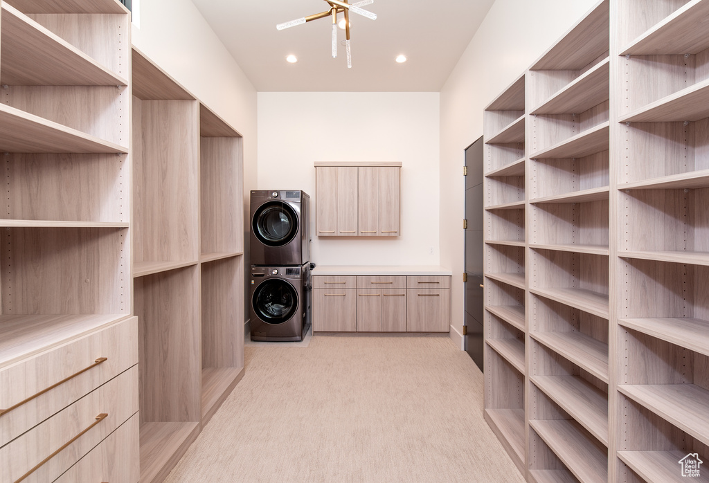 Spacious closet with light colored carpet, ceiling fan, and stacked washer and clothes dryer