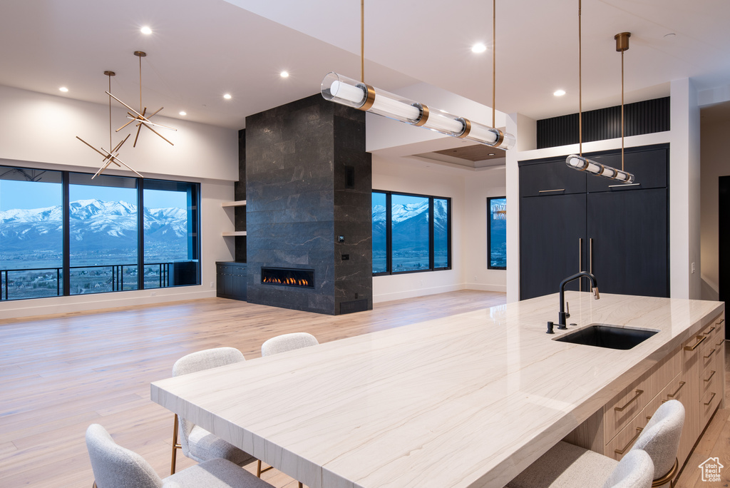 Kitchen featuring a mountain view, pendant lighting, a tiled fireplace, sink, and light hardwood / wood-style floors