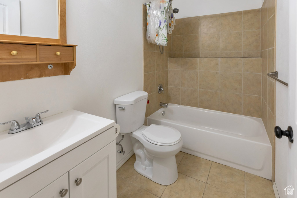 Full bathroom with tile floors, vanity, tiled shower / bath combo, and toilet
