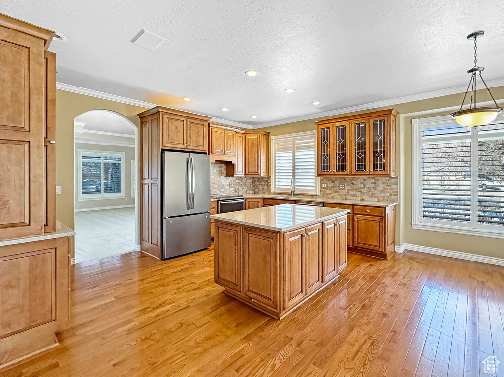 Kitchen featuring light hardwood / wood-style floors, a center island, decorative light fixtures, and stainless steel fridge