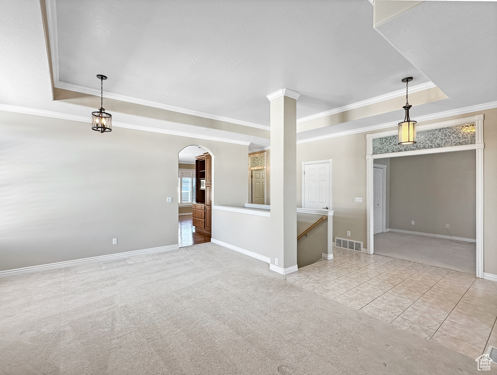 Spare room with ornamental molding, light tile floors, and a tray ceiling