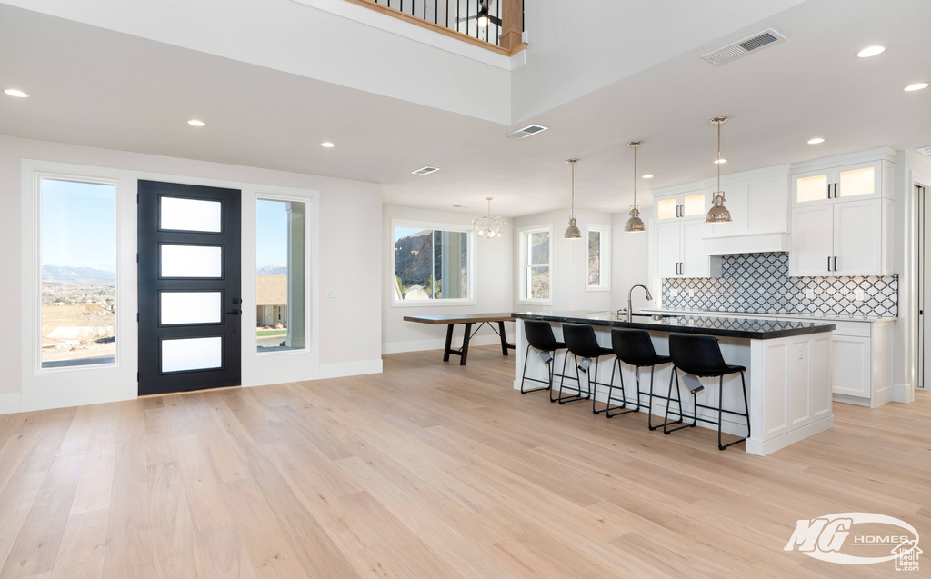 Kitchen featuring white cabinets, light hardwood / wood-style flooring, backsplash, and a healthy amount of sunlight