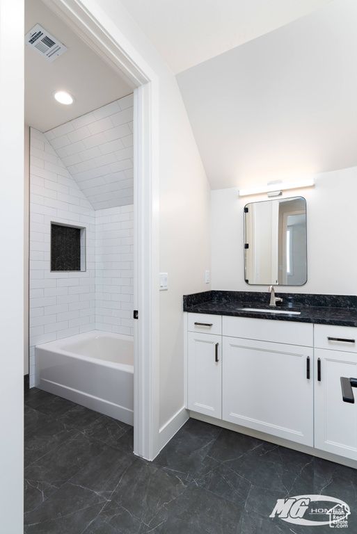 Bathroom featuring vanity, lofted ceiling, tiled shower / bath combo, and tile floors