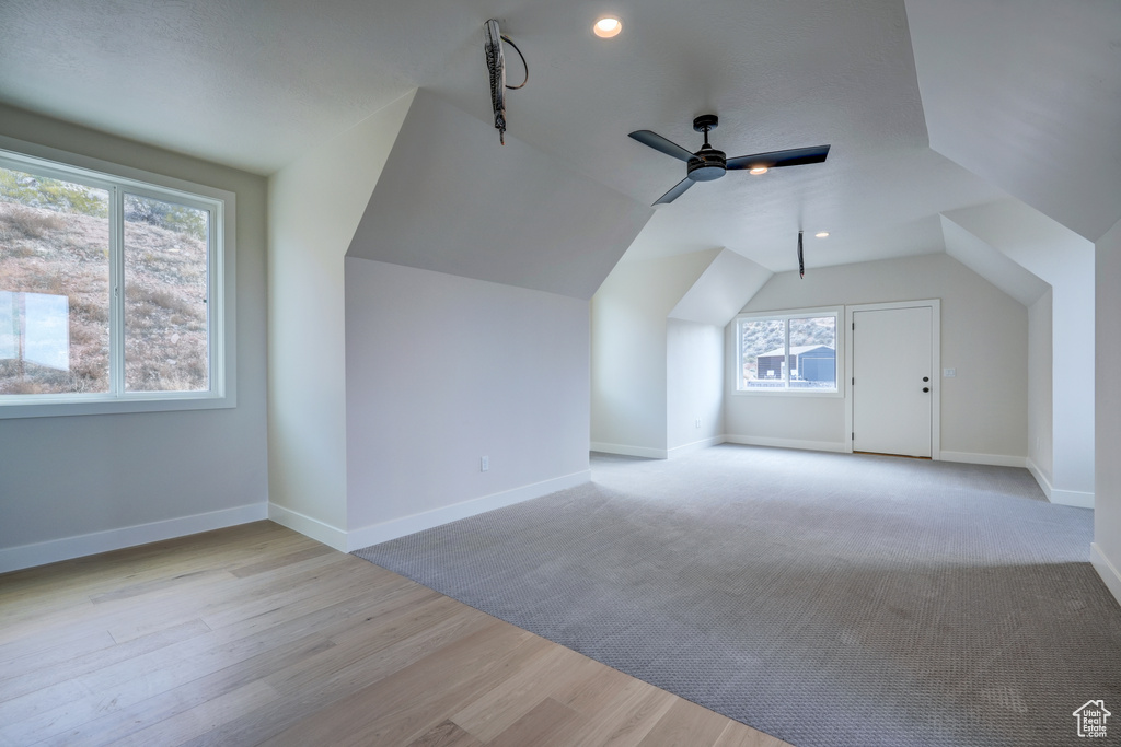 Bonus room with lofted ceiling, ceiling fan, and light wood-type flooring