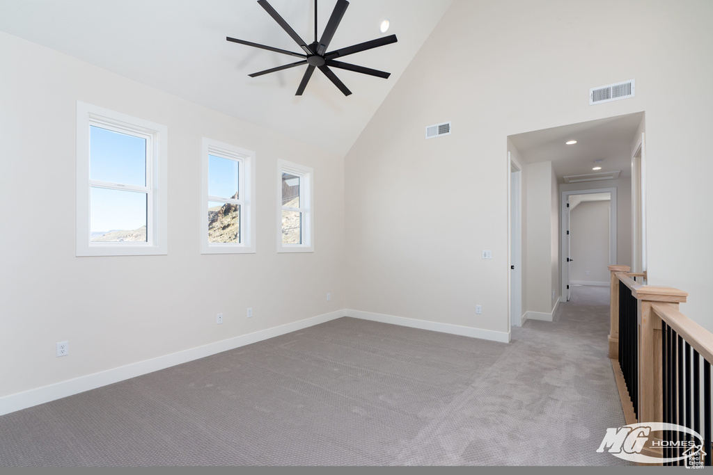 Empty room with light carpet and high vaulted ceiling