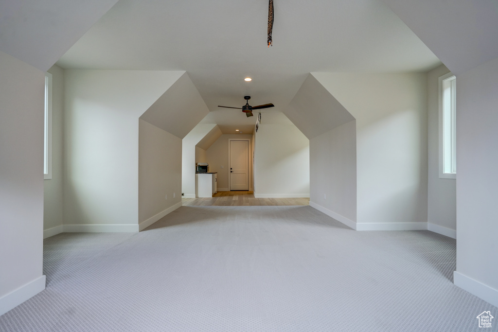 Additional living space with light carpet, ceiling fan, and lofted ceiling