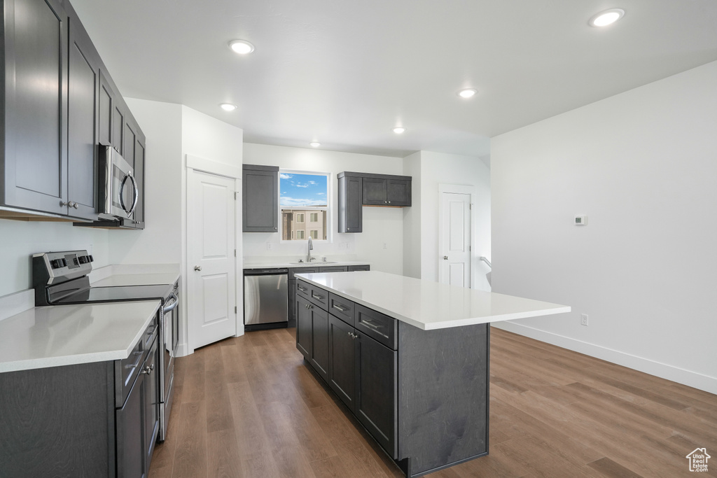Kitchen featuring a center island, sink, stainless steel appliances, and dark hardwood / wood-style floors