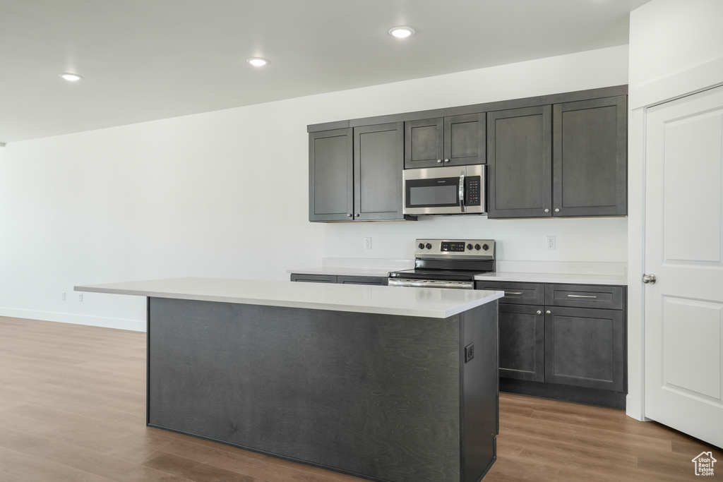 Kitchen featuring appliances with stainless steel finishes, wood-type flooring, and a center island