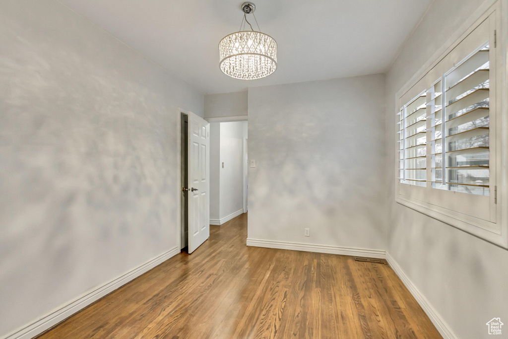 Unfurnished room featuring a chandelier and hardwood / wood-style flooring