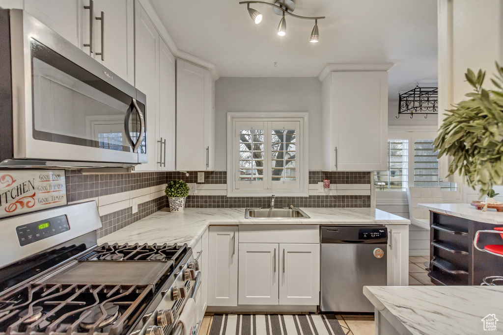 Kitchen featuring white cabinets, sink, appliances with stainless steel finishes, and a healthy amount of sunlight