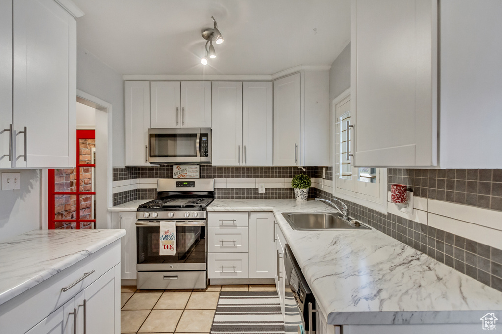 Kitchen with white cabinetry, sink, appliances with stainless steel finishes, and backsplash