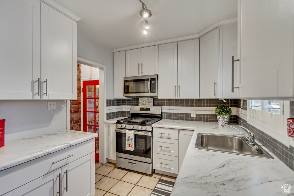 Kitchen featuring white cabinets, appliances with stainless steel finishes, sink, and tasteful backsplash