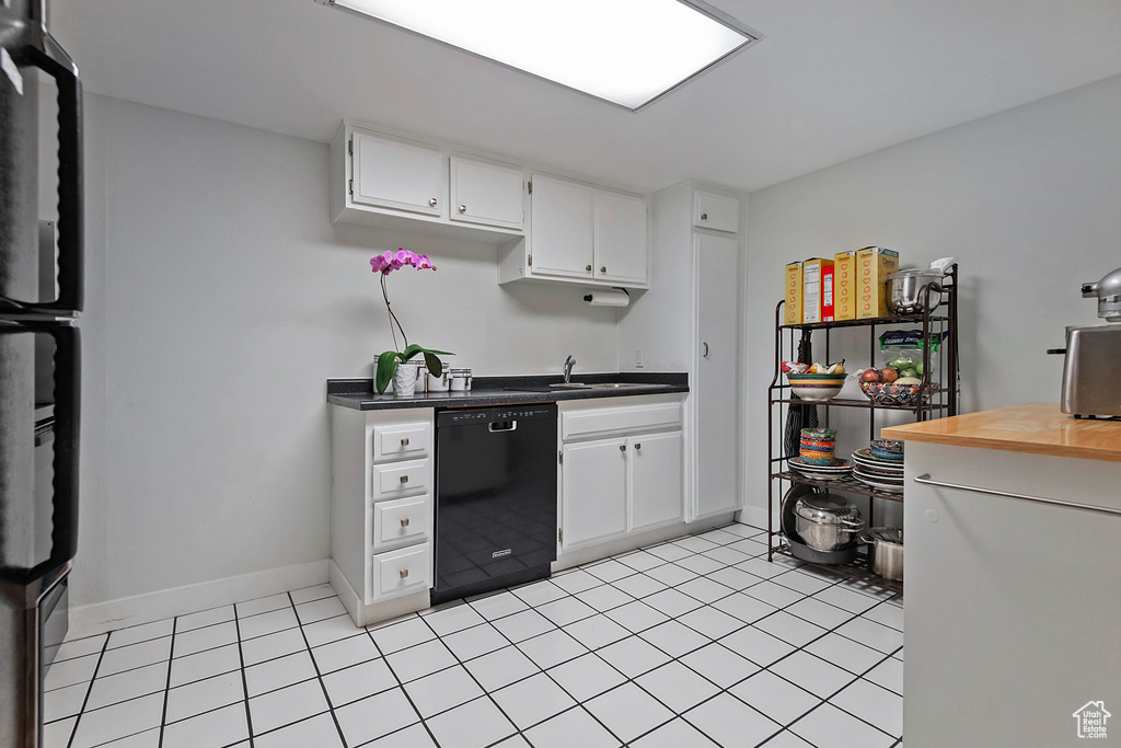 Kitchen with black dishwasher, sink, light tile floors, and white cabinets