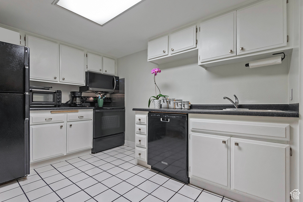 Kitchen with light tile flooring, black appliances, and white cabinetry