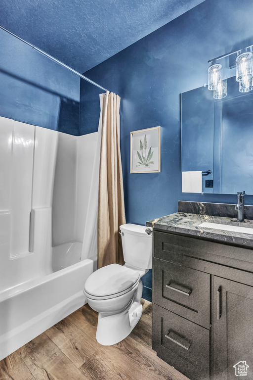 Full bathroom with shower / bath combo, hardwood / wood-style floors, oversized vanity, and toilet