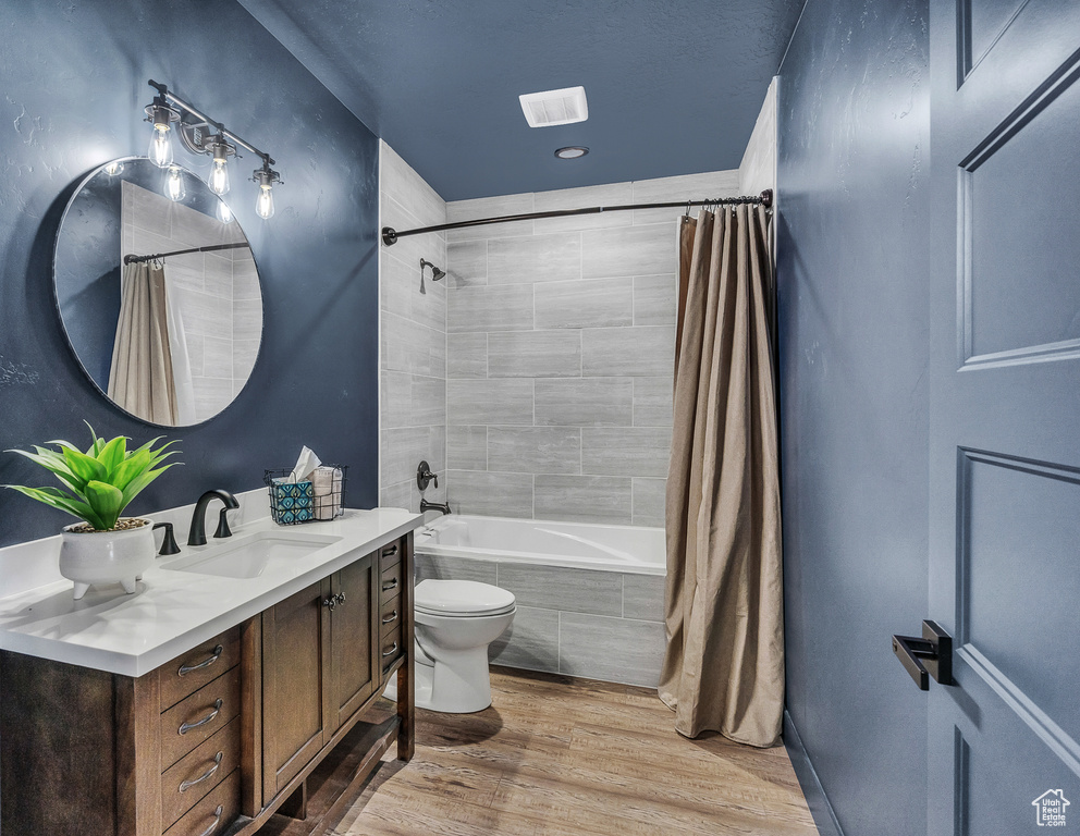 Full bathroom featuring vanity, shower / bath combo, hardwood / wood-style flooring, and toilet