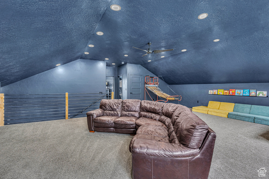 Cinema room featuring ceiling fan, a textured ceiling, carpet, and vaulted ceiling