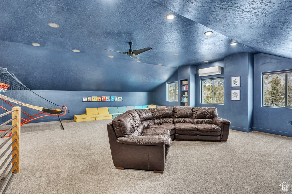 Cinema with a wall mounted AC, light carpet, a textured ceiling, vaulted ceiling, and ceiling fan