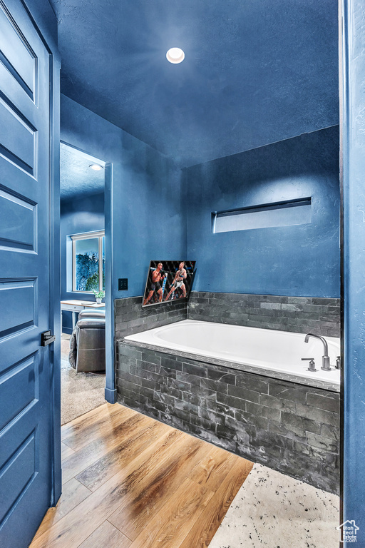 Bathroom featuring tiled bath and hardwood / wood-style flooring