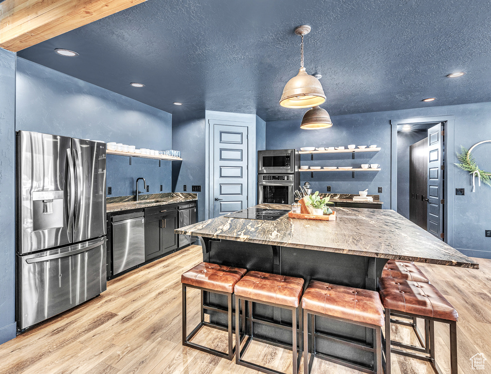 Kitchen featuring light hardwood / wood-style floors, stainless steel appliances, and a kitchen breakfast bar