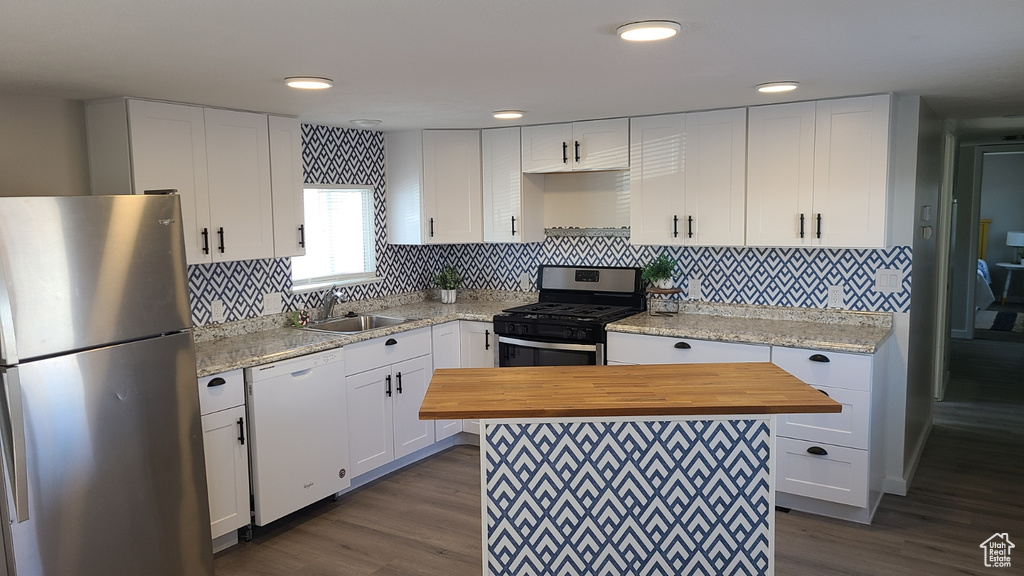 Kitchen with white cabinetry, tasteful backsplash, dark hardwood / wood-style floors, sink, and stainless steel appliances
