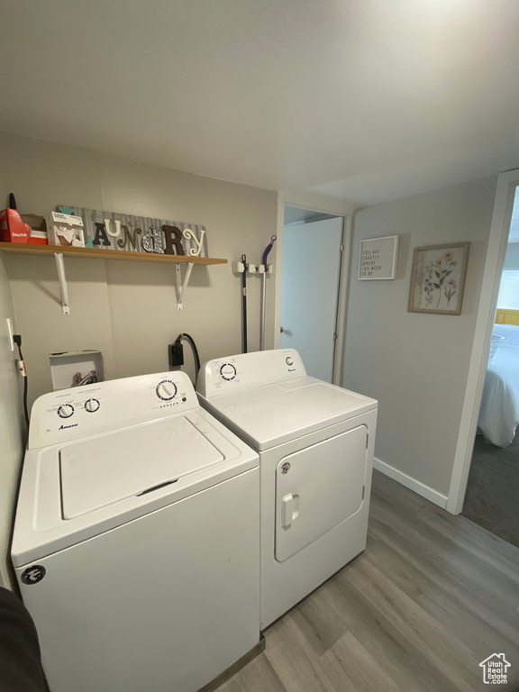 Laundry room featuring washing machine and dryer, hookup for an electric dryer, hookup for a washing machine, and light hardwood / wood-style flooring