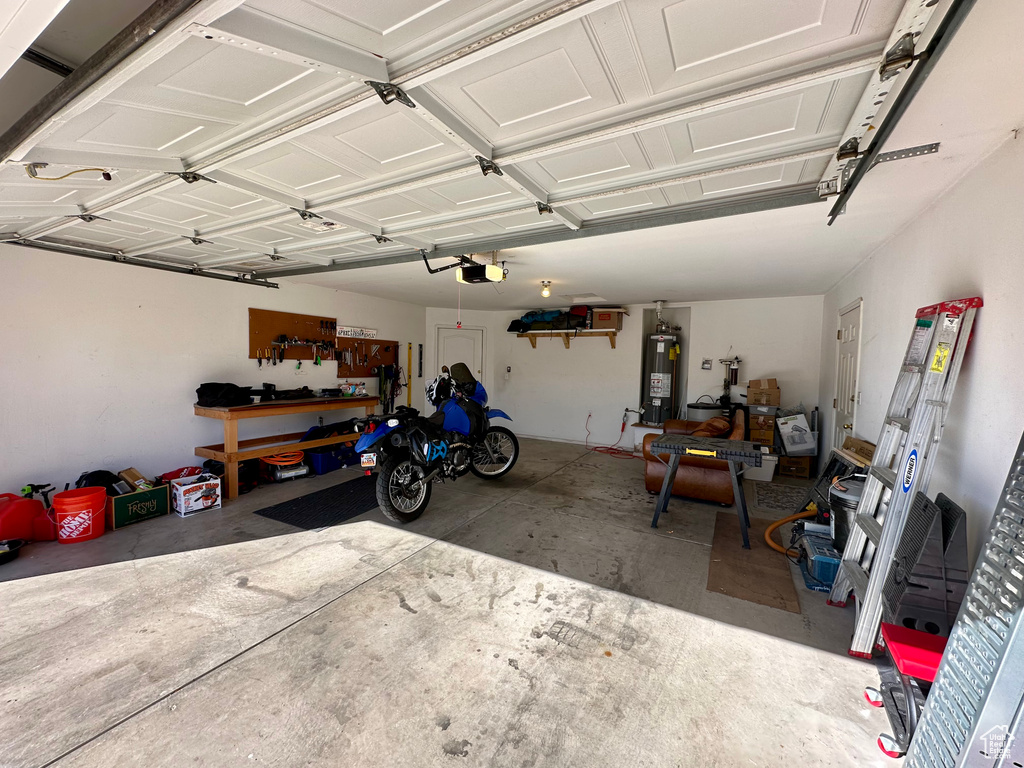 Garage featuring water heater, a workshop area, and a garage door opener