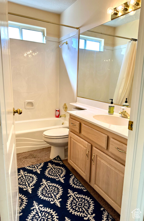 Full bathroom with plenty of natural light, large vanity, shower / bath combo with shower curtain, and toilet