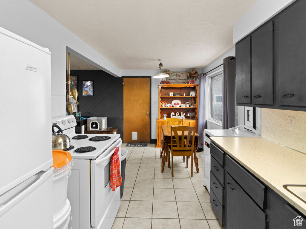 Kitchen featuring white appliances, washer / clothes dryer, and light tile floors