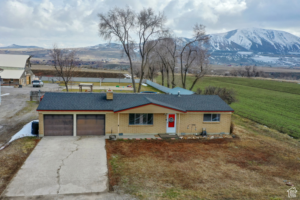 Ranch-style home with a mountain view, a front yard, and a garage