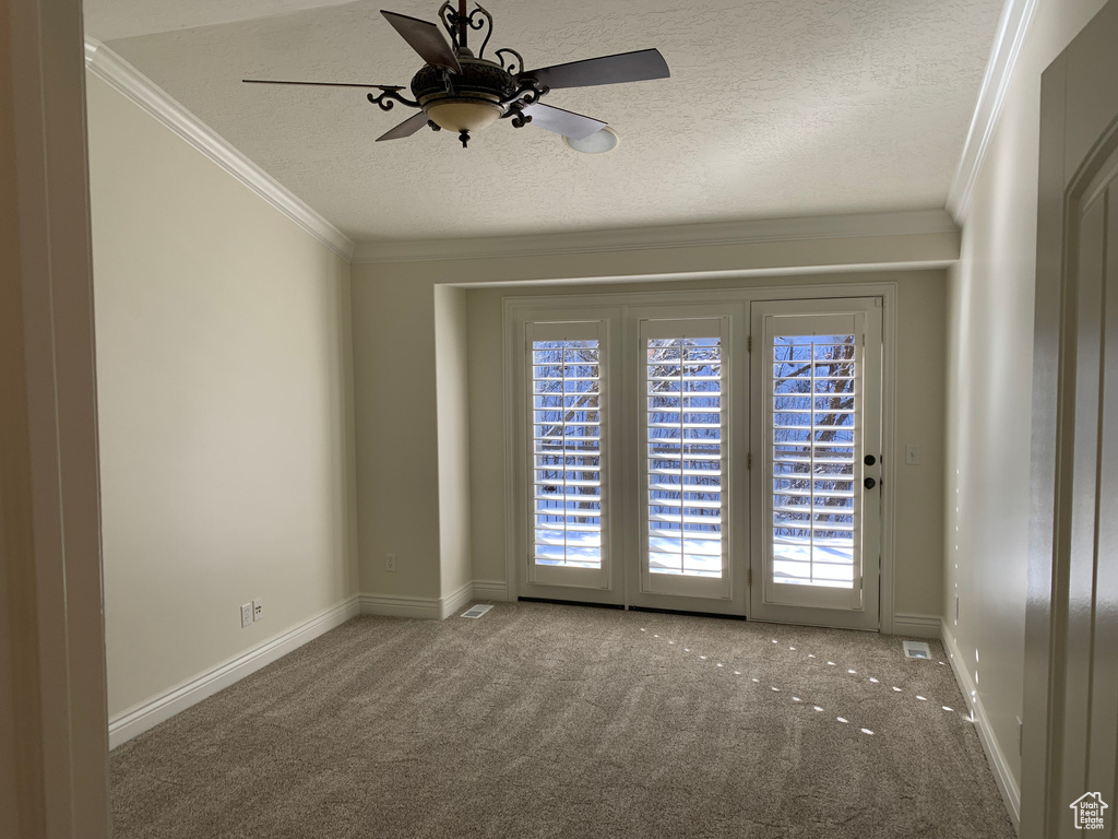 Carpeted empty room with crown molding, ceiling fan, and a textured ceiling