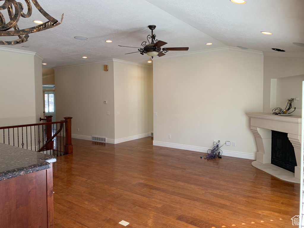 Unfurnished living room featuring dark hardwood / wood-style floors, ceiling fan, ornamental molding, and lofted ceiling
